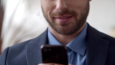 有吸引力的商人发短信细胞电话微笑男人。发短信智能手机